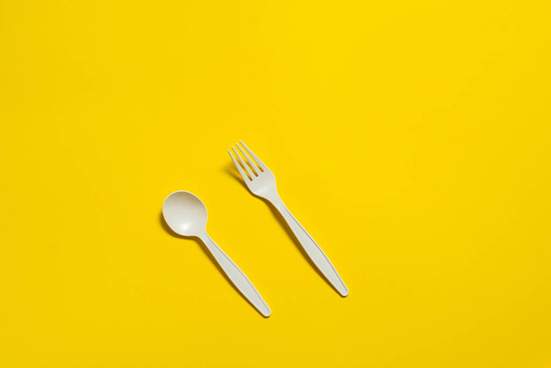 disposable eco-friendly fork and spoon made of corn starch on a yellow background. isolate. biodegradable picnic tableware. place for text. - Photo, Image