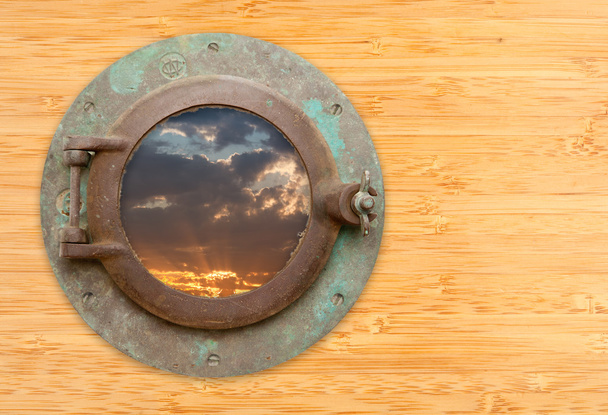 Антикварный иллюминатор с видом на закат на бамбуковой стене
 - Фото, изображение