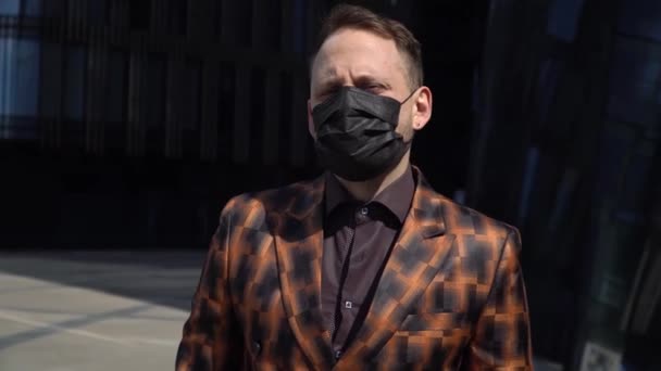 A European man in the background of a business center stands in a medical mask and looks around. The concept of reirting sadness. - Footage, Video