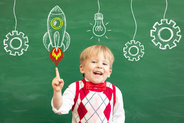 Bright idea! Funny child student pointing finger up! Happy kid against green chalkboard. Online education and e-learning concept. Back to school - Photo, Image