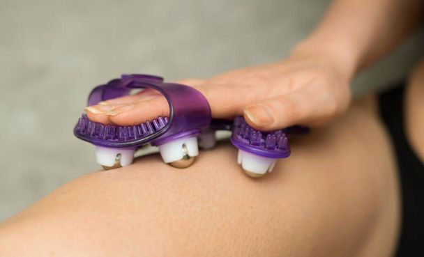 Woman massaging herself with manual massage roller glove. - Photo, Image