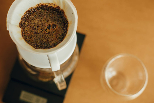 Пивоваріння ароматичної свіжої кави в паперовому фільтрі крупним планом вливається в масштаб. Альтернативна кавоварка v60 крупним планом. Бариста робить фільтрувальну каву на коричневому фоні
 - Фото, зображення