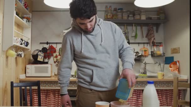 A young man is cooking breakfast in the kitchen - Imágenes, Vídeo