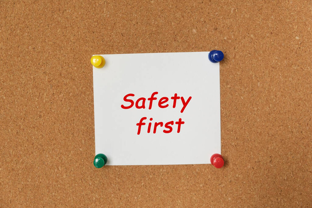 Text Safety first written on a sticker pinned on a cork board - Foto, Imagen