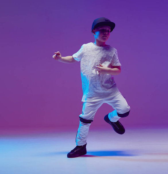 Cool young boy child dancing hip hop in the Studio against the background of neon lights. Break dance poster. - Фото, изображение