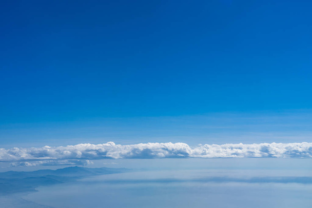 雲、山脈、青い空の背景を持つ海岸線 - 写真・画像
