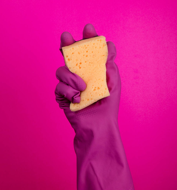  Hand in a latex glove isolated. A hand in a glove holds a sponge for washing and cleaning. Cleaning or housekeeping concept background. Frame for text or advertising. colorful background - 写真・画像