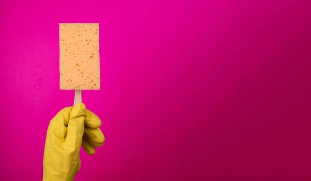 Sponge popsicle on a stick isolated .Sponge for washing dishes in hand. Hand in a latex glove isolated. A hand in a glove holds a sponge for washing and cleaning. Cleaning or housekeeping concept background. Frame for text or advertising - Photo, Image