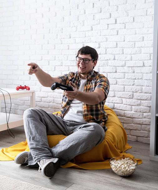 Смішний молодий чоловік грає у відеоігри вдома
 - Фото, зображення