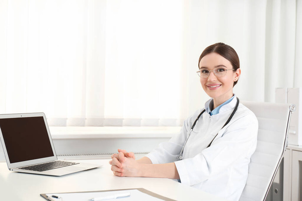Retrato de jovem médica no casaco branco no local de trabalho
 - Foto, Imagem
