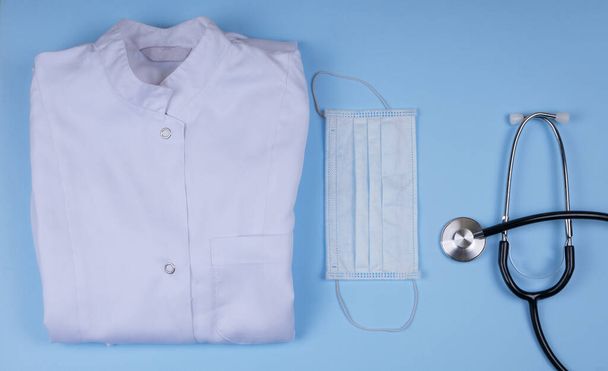 white medical dressing gown on blue background - Zdjęcie, obraz