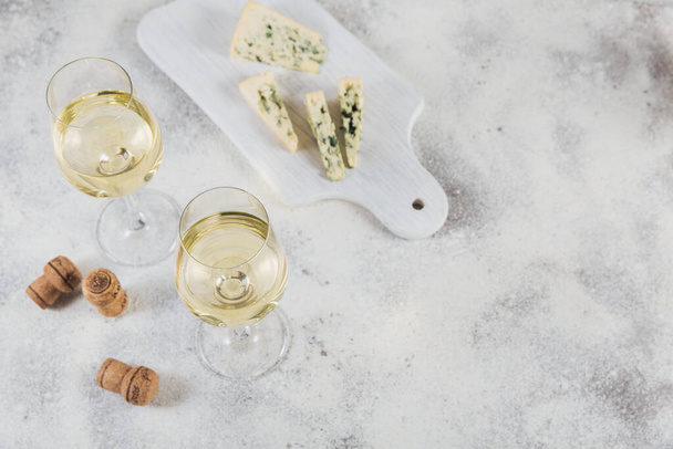 White wine served with cheese plate on light background. Two wineglasses of vino verde. Seasonal holidays concept. - Foto, Imagem