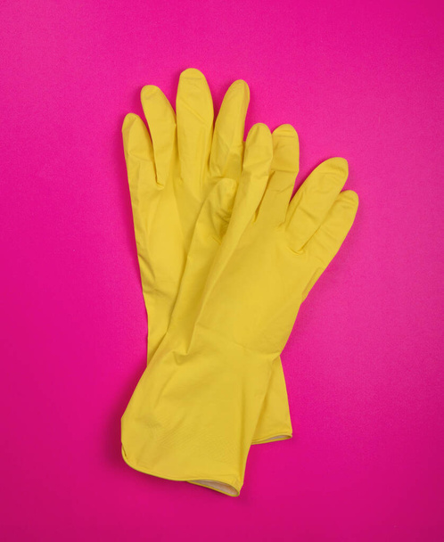 color rubber gloves for cleaning on pink background, workhouse concept. Commercial cleaning company. Employee hands in color rubber protective glove. General or regular cleanup.  - Foto, imagen