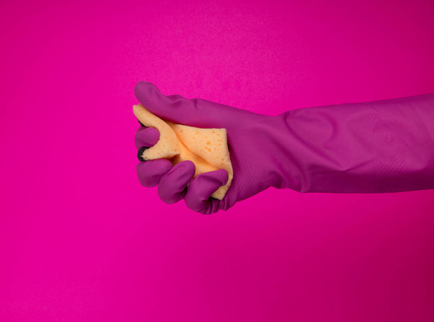 Sponge for washing dishes in hand. Hand in a latex glove isolated. A hand in a glove holds a sponge for washing and cleaning. Cleaning or housekeeping concept background. Frame for text or advertising - Photo, Image