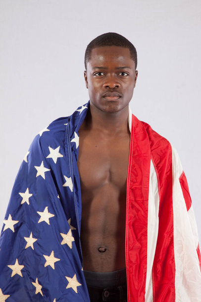 Przystojny czarny mężczyzna bez koszuli z flagą Stanów Zjednoczonych na ramionach - Zdjęcie, obraz