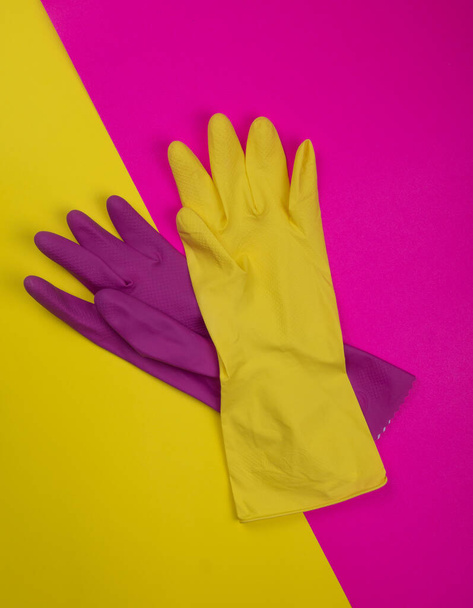 color rubber gloves for cleaning on pink background, workhouse concept. Commercial cleaning company. Employee hands in color rubber protective glove. General or regular cleanup.  - Photo, Image