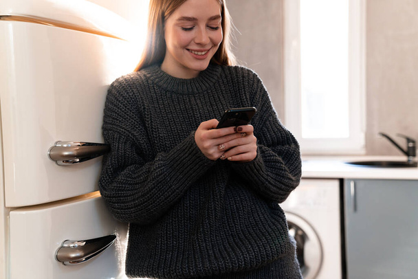 Image of a cheerful happy positive young woman indoors at home using mobile phone. - Φωτογραφία, εικόνα