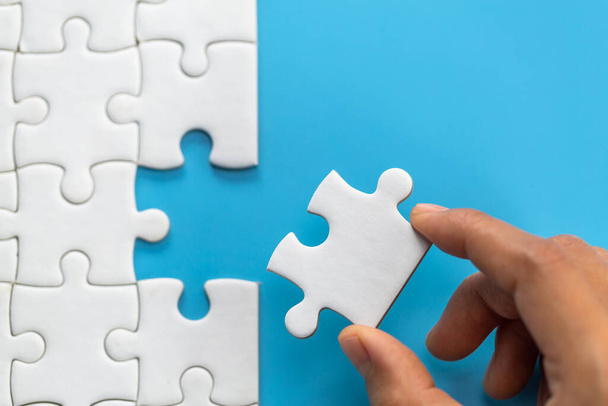 Зв'язок між головоломками з білими плямами, головоломка з'являється в руці бізнесмена, бізнес команда збирає головоломки Jigsaw. - Фото, зображення