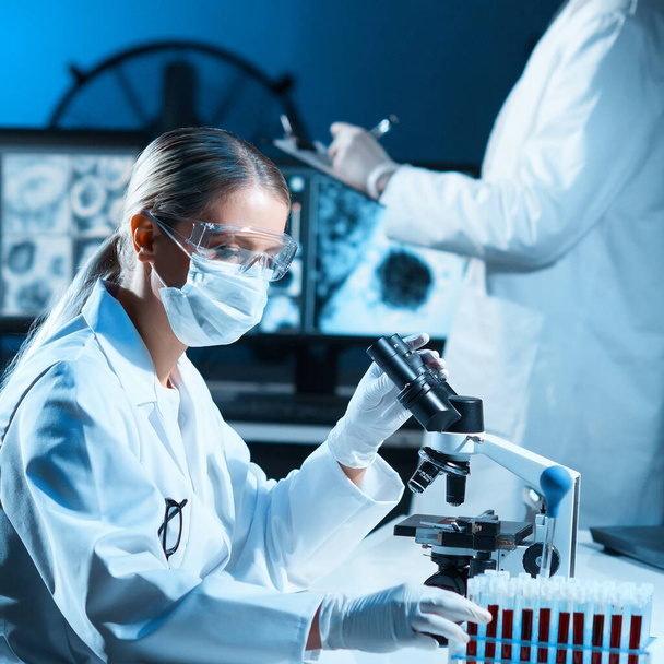 Scientists working in modern lab. Doctor making microbiology research. Laboratory tools: microscope, test tubes, equipment. Bacteriology, virology and health care concept. - Foto, Bild