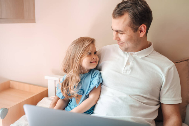 Father and kid girl using laptop at home looking at screen choosing goods online, happy dad talking to child daughter showing new computer application watching video, doing internet shopping together - Φωτογραφία, εικόνα