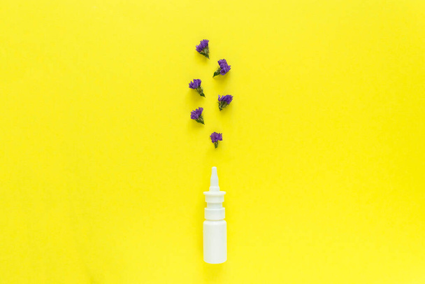 Seasonal spring summer allergy flowers concept. White spray container with purple flowers on yellow background. Creative flat lay composition, copy space, minimal style - Foto, Imagen