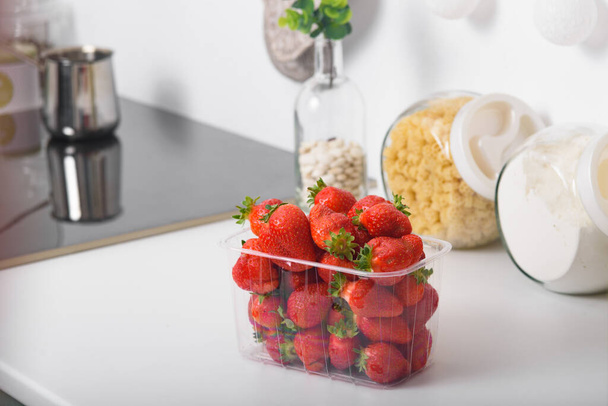 Čerstvé organické jahody v plastové krabici v kuchyni. dodávky ekologických produktů. balení ekologických jahod. V kuchyni. - Fotografie, Obrázek