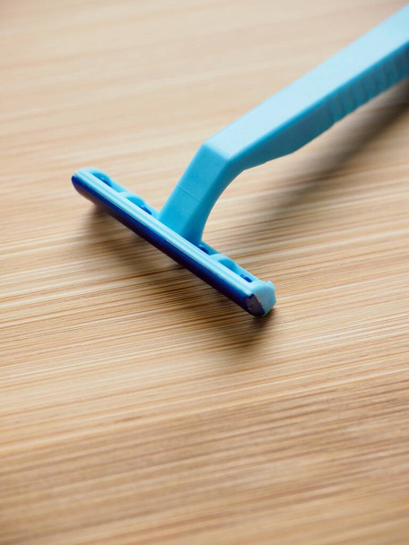 Rasoir jetable bleu avec fond en bois
 - Photo, image