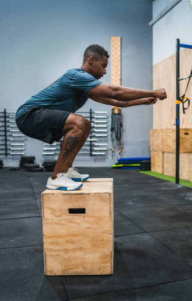 Portrait of an athletic man doing box jump exercise. Crossfit, sport and healthy lifestyle concept. - Fotó, kép