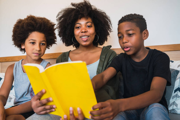 Portrait of Afro American mother reading a book to her children at home. Family and lifestyle concept. - Foto, immagini