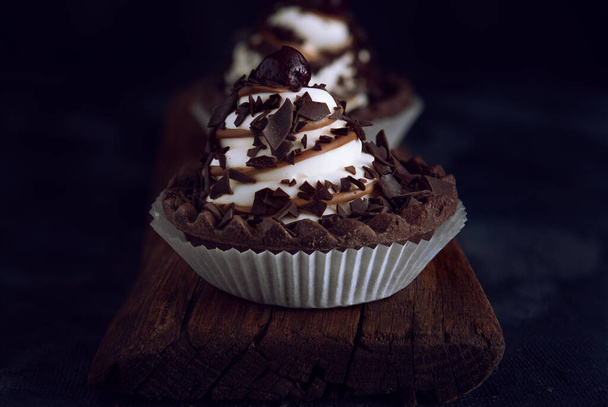 Шоколадное печенье со сливками и вишней на темном фоне
 - Фото, изображение