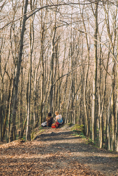 dvě přítelkyně sedící na zemi u útesu v lese. koncepce jarní turistiky - Fotografie, Obrázek