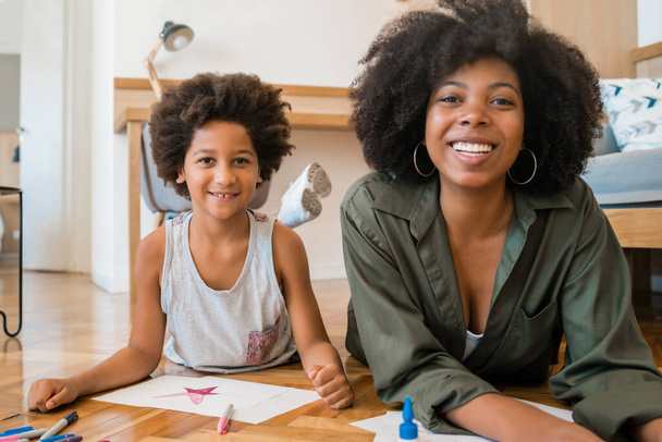Portrait of young african american mother and son drawing with colored pencils on warm floor at home. Family concept. - Photo, image