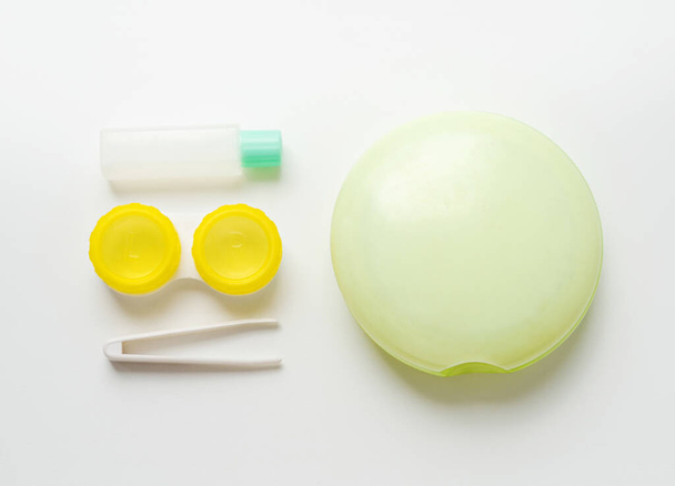 Kit per la cura delle lenti a contatto su fondo chiaro: contenitore, pinzette, soluzione, custodia
 - Foto, immagini
