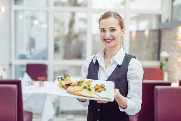Camarera en un bonito restaurante presentando un sabroso plato
 - Foto, imagen
