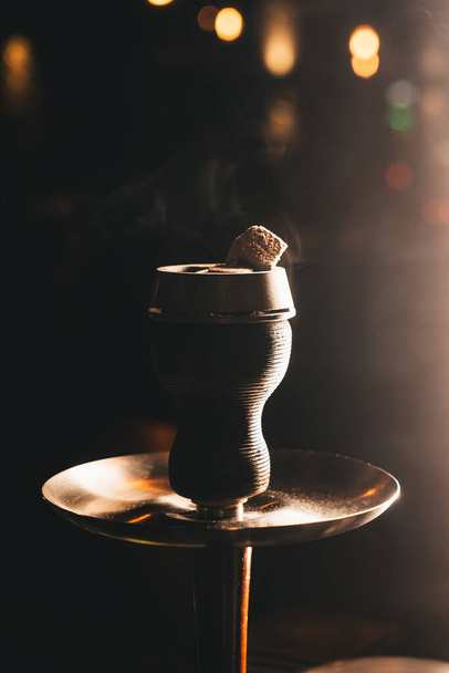 Gros plan du bol de narguilé avec du tabac et des charbons à l'intérieur, avec une lumière douce et chaude
  - Photo, image