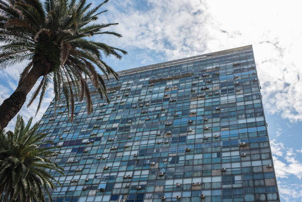 Montevideo / Uruguay, 29. Dezember 2018: Außenansicht eines verglasten Gebäudes mit vielen aufgehängten Klimaanlagen, Palmen und sonnigem Himmel - Foto, Bild