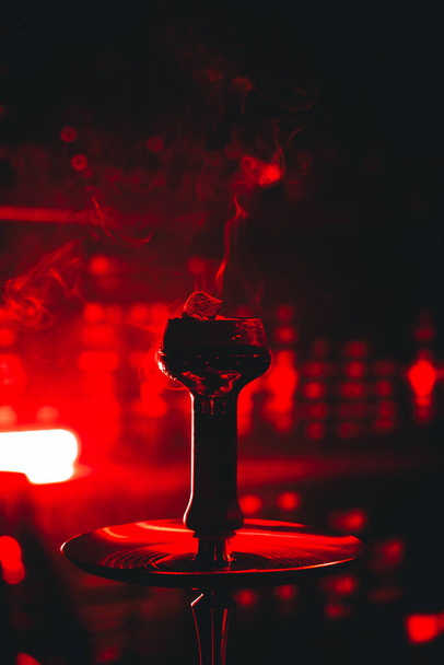 Dampfende Wasserpfeife im roten Neonlicht einer Bar, Lust-Vibe - Foto, Bild