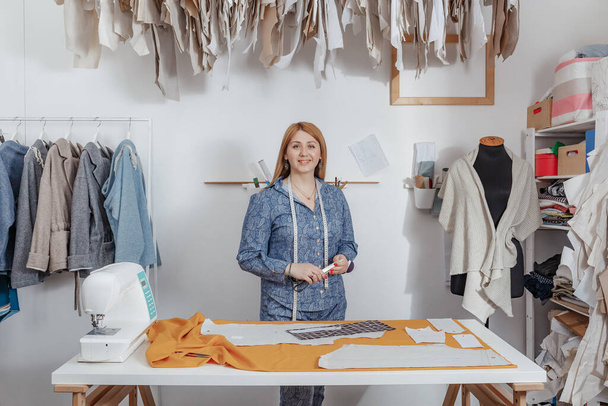 Portrait of happy young lady fashion designer smiling standing in workshop alone looking at camera. Small business owner and successful youth concept. - Фото, зображення