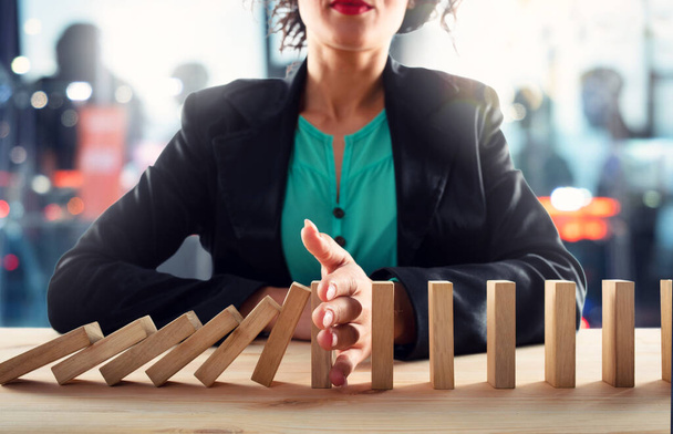 Businesswoman stops a chain fall like domino game. Concept of preventing crisis and failure in business. - Photo, Image