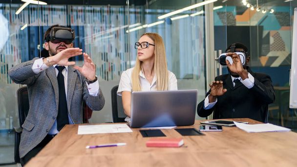 Pessoas de negócios usando óculos de realidade virtual durante a reunião. Equipe de desenvolvedores testando headset de realidade virtual e discutindo novas ideias para melhorar a experiência visual. - Foto, Imagem