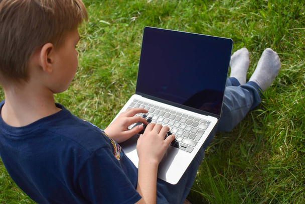The student learns in the garden on the computer. The online schooling - Фото, изображение