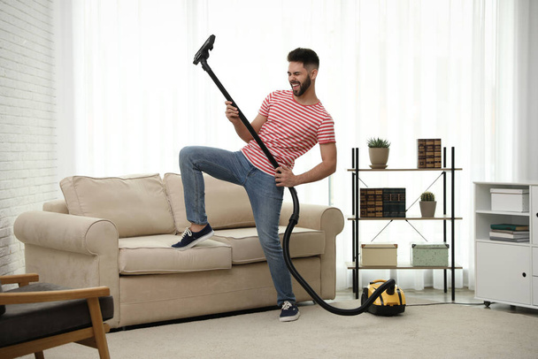 Young man having fun while vacuuming at home - Foto, immagini
