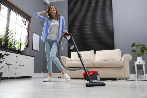 Young woman having fun while vacuuming at home - Zdjęcie, obraz