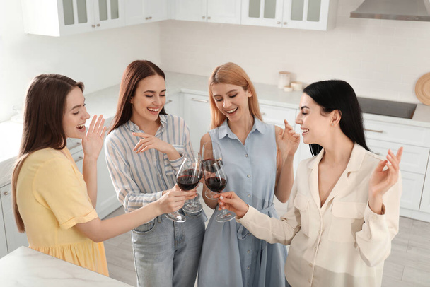 Beautiful young ladies clinking glasses of wine in kitchen. Women's Day - Φωτογραφία, εικόνα