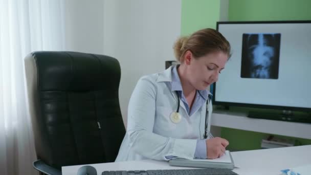 funcionário do hospital feminino trabalha remotamente com pacientes, escreve sintomas de doença ou frio no cartão médico, colocando aconselhamento on-line via link de vídeo
 - Filmagem, Vídeo