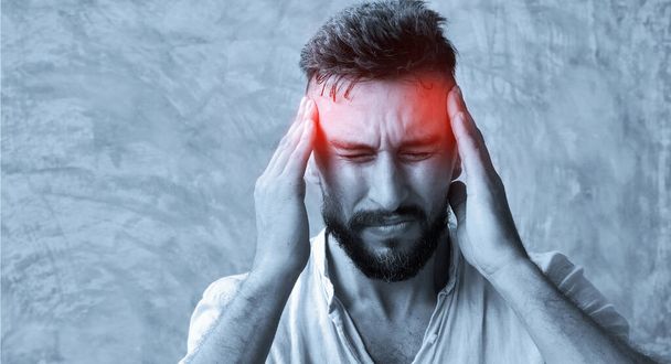 Een man die hoofdpijn heeft van een pijnlijke hoofdpijn en er moe, bezorgd en stressvol uitziet - Foto, afbeelding