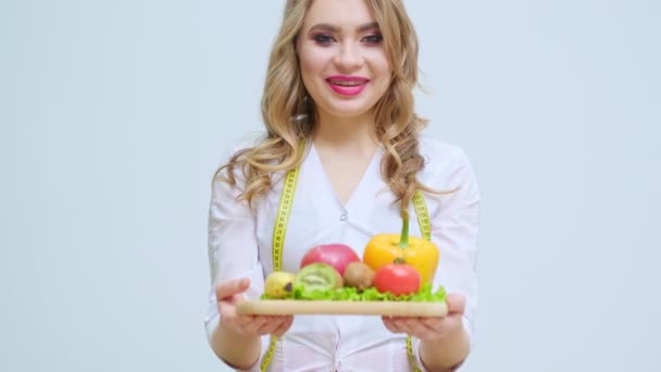 Pojęcie zdrowego odżywiania, kobieta dietetyk w klinice z różnych warzyw i owoców - Materiał filmowy, wideo