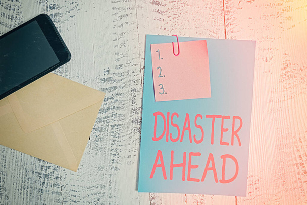 Text sign showing Disaster Ahead. Conceptual photo Contingency Planning Forecasting a disaster or incident Envelope blank sheet paper sticky note smartphone wooden vintage background. - Photo, Image
