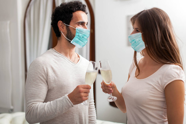 Man and woman wearing masks toasting with champagne - Foto, imagen