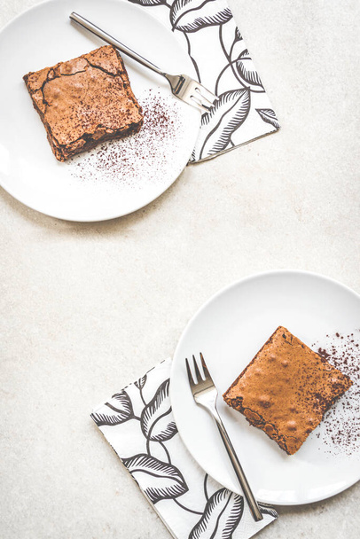 Horní pohled na dva dezertní talíře s brownie dort přes bílé rustikální pozadí. - Fotografie, Obrázek